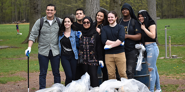 A group of students smiling during a park cleanup event.