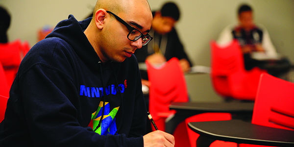 A student sitting in class and writing.