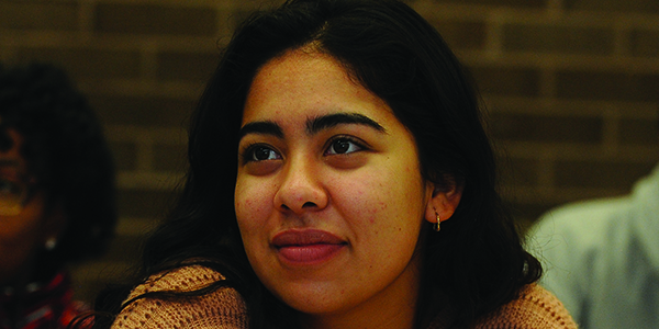 A student sitting in class and looking forward attentively.