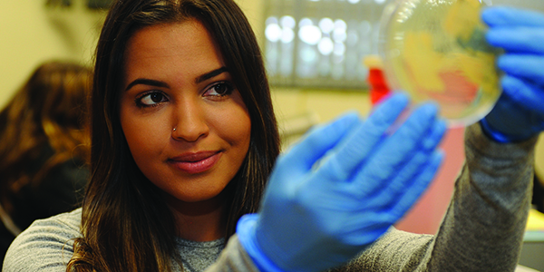A student in a science lab holding a petri dish.