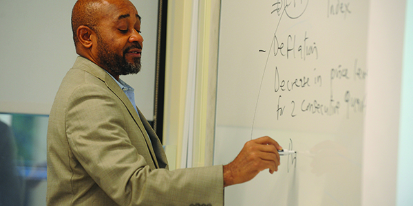 A professor writing on the board in a classroom.