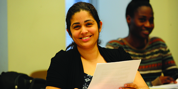 A student smiling while holding a piece of paper.
