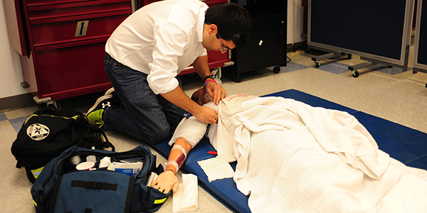 A student working with a medical training mannequin.