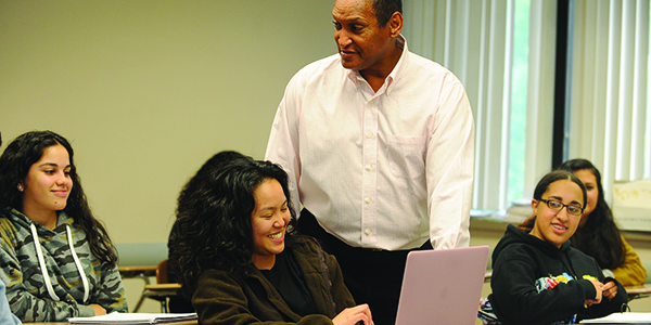 A professor talking with students in a classroom.