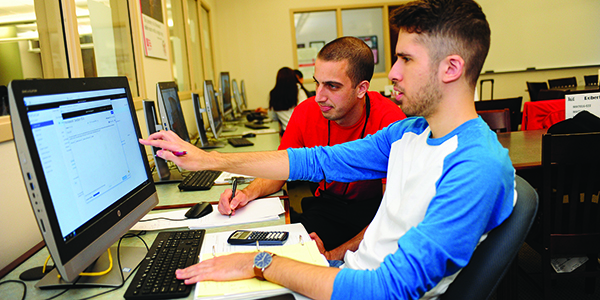Two students working together on a desktop computer.