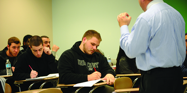 A professor lecturing in the front of the classroom.