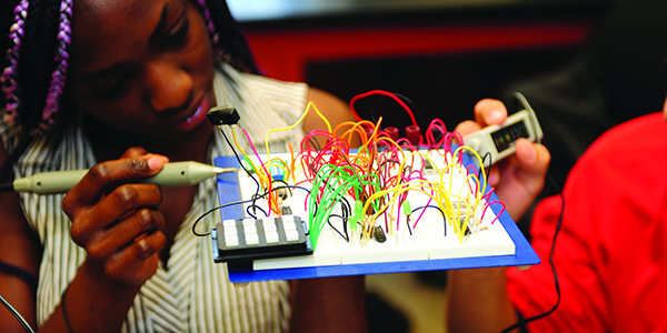 Two students working on a technical model with wires.