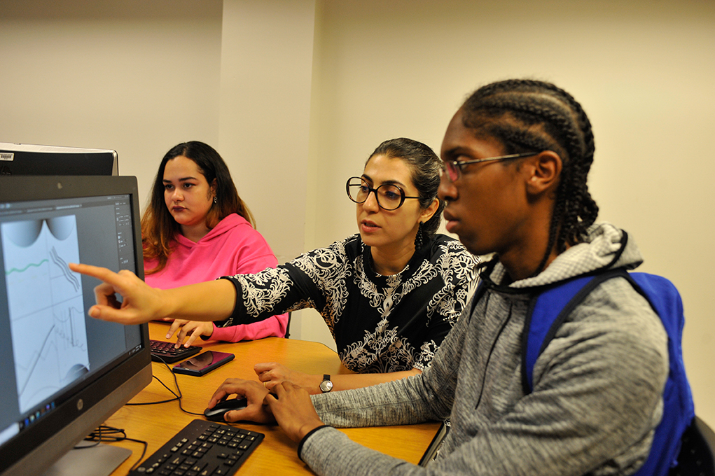 A professor helping a student with a project on a computer.